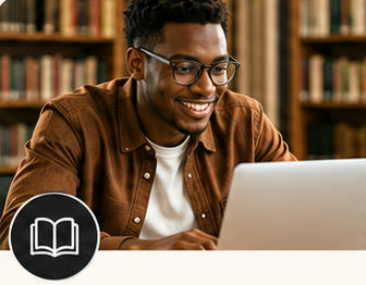 Un étudiant à lunettes travaille sur son ordinateur dans une bibliothèque.
